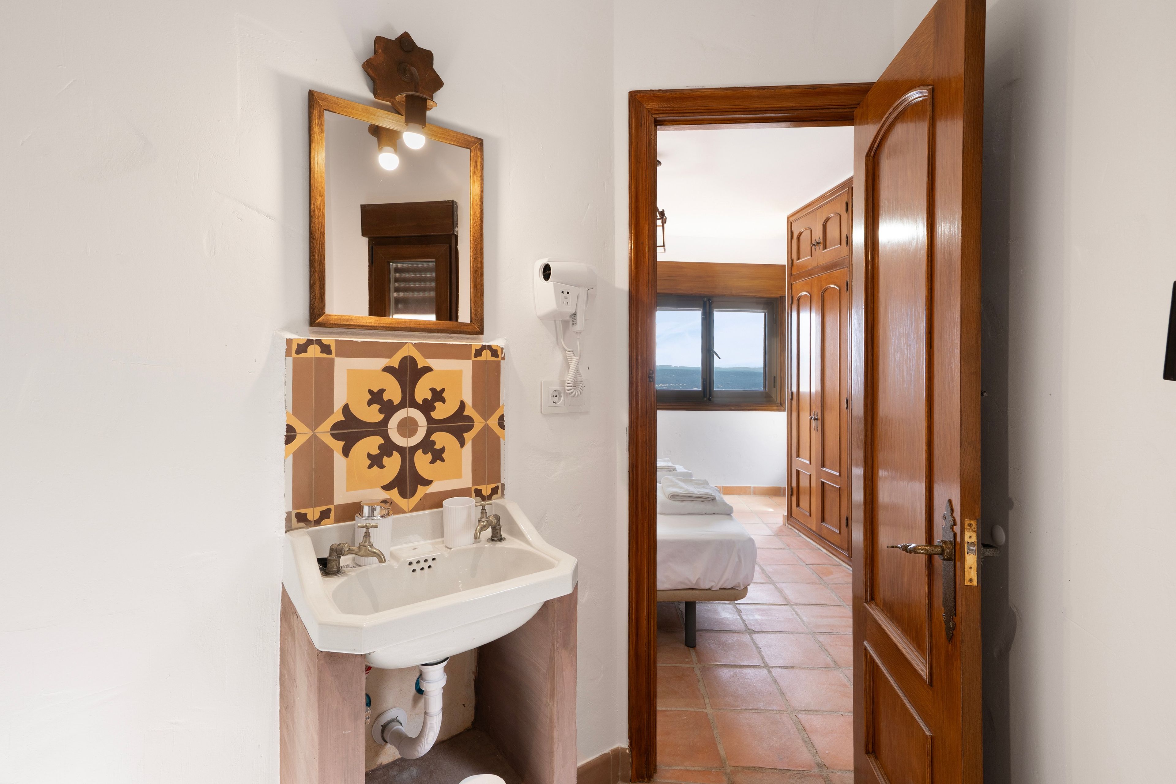 A bathroom with a sink, mirror, and a hairdryer on the wall.
