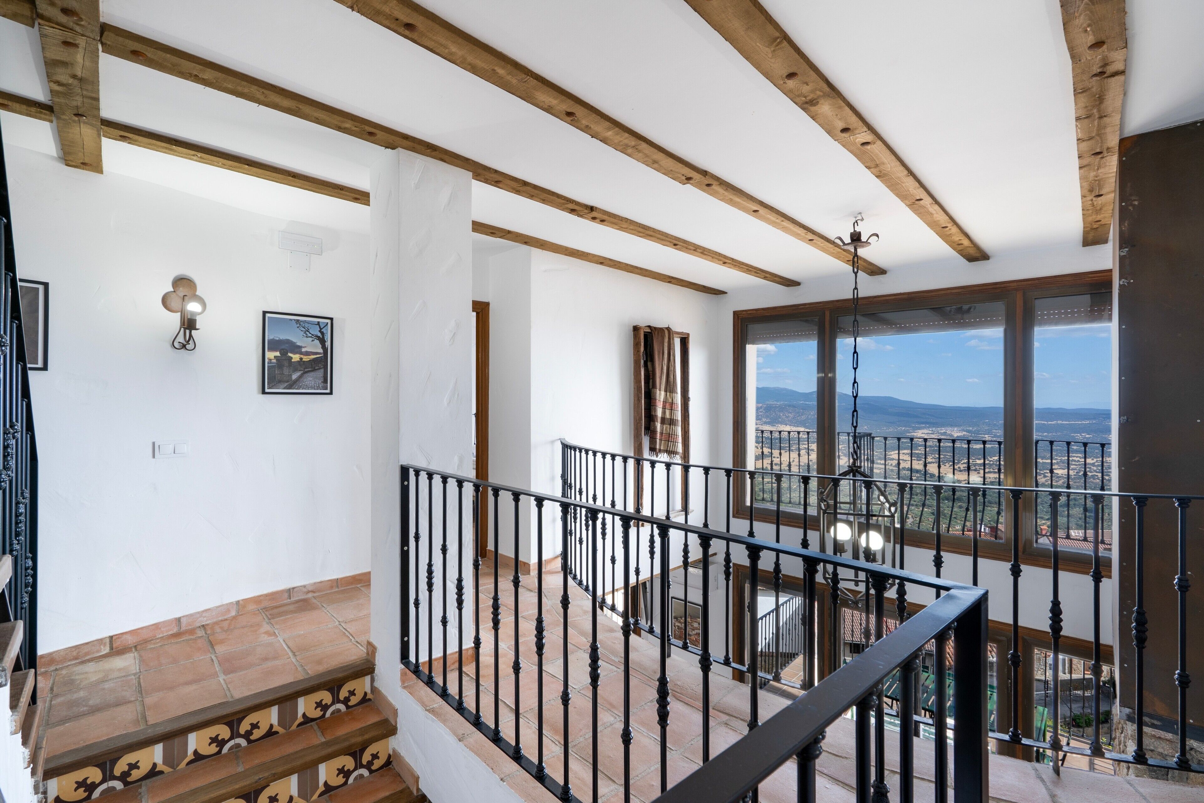 A staircase with a black railing leading to a balcony with a view of a landscape.