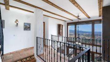 A staircase with a black railing leading to a balcony with a view of a landscape.