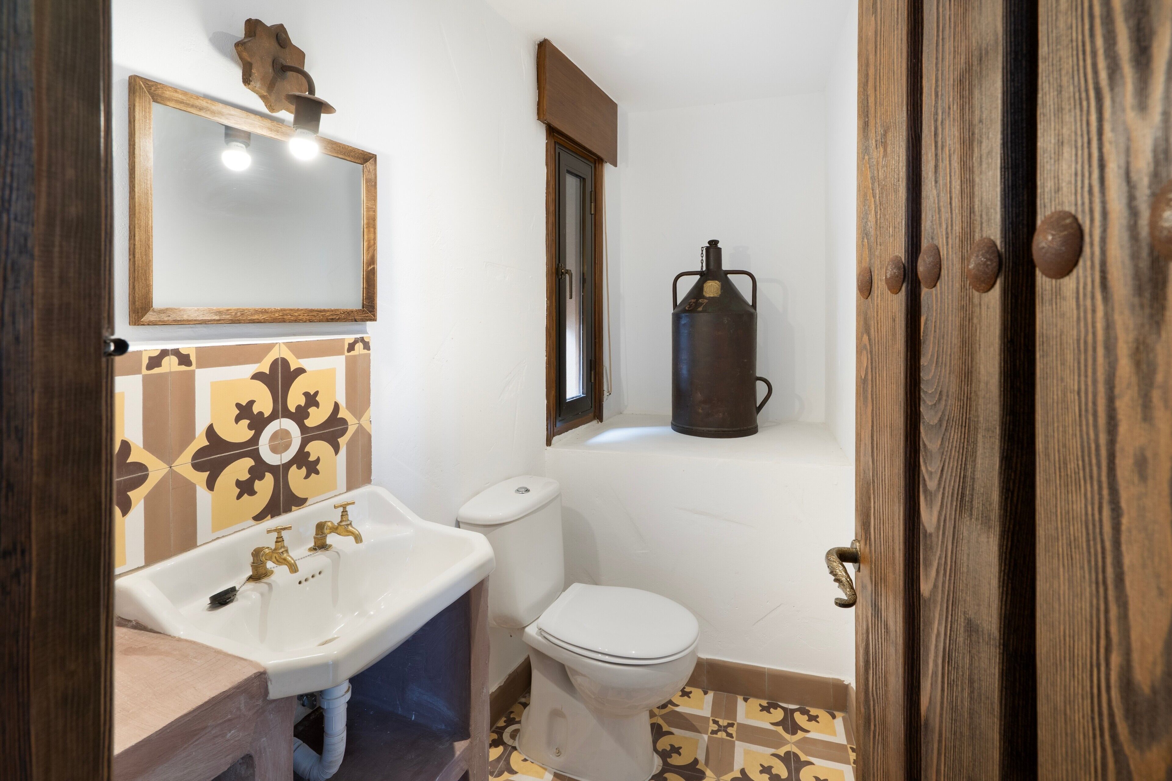 A bathroom with a sink, toilet, and a mirror.