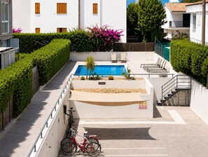 Ein Poolbereich mit einem roten Fahrrad, einer Treppe und einem weißes Gebäude mit Fenstern.
