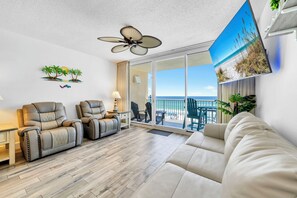 A modern living room with a sofa, two recliners, a ceiling fan, and a balcony with a view of the beach. - ⛱️Beachfront | 5 Pools | Majestic Beach Towers 2-407⛱️ (Panama City Beach)