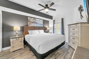 A bedroom with a bed, nightstands, a dresser, a ceiling fan, and a painting on the wall. - ⛱️Beachfront | 5 Pools | Majestic Beach Towers 2-407⛱️ (Panama City Beach)