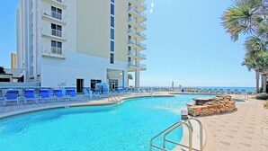 Una piscina con sedie blu, una struttura in pietra e un edificio con balconi.