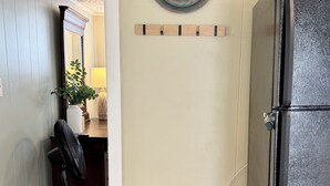 Une petite cuisine équipée d’un réfrigérateur, d’un banc et d’une assiette décorative accrochée au mur.
