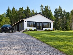 A modern two-story house with a gravel driveway and a well-maintained lawn.