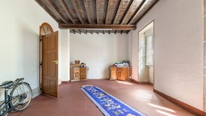 A hallway with a wooden door, a bicycle, a blue patterned rug, and a wooden cabinet.