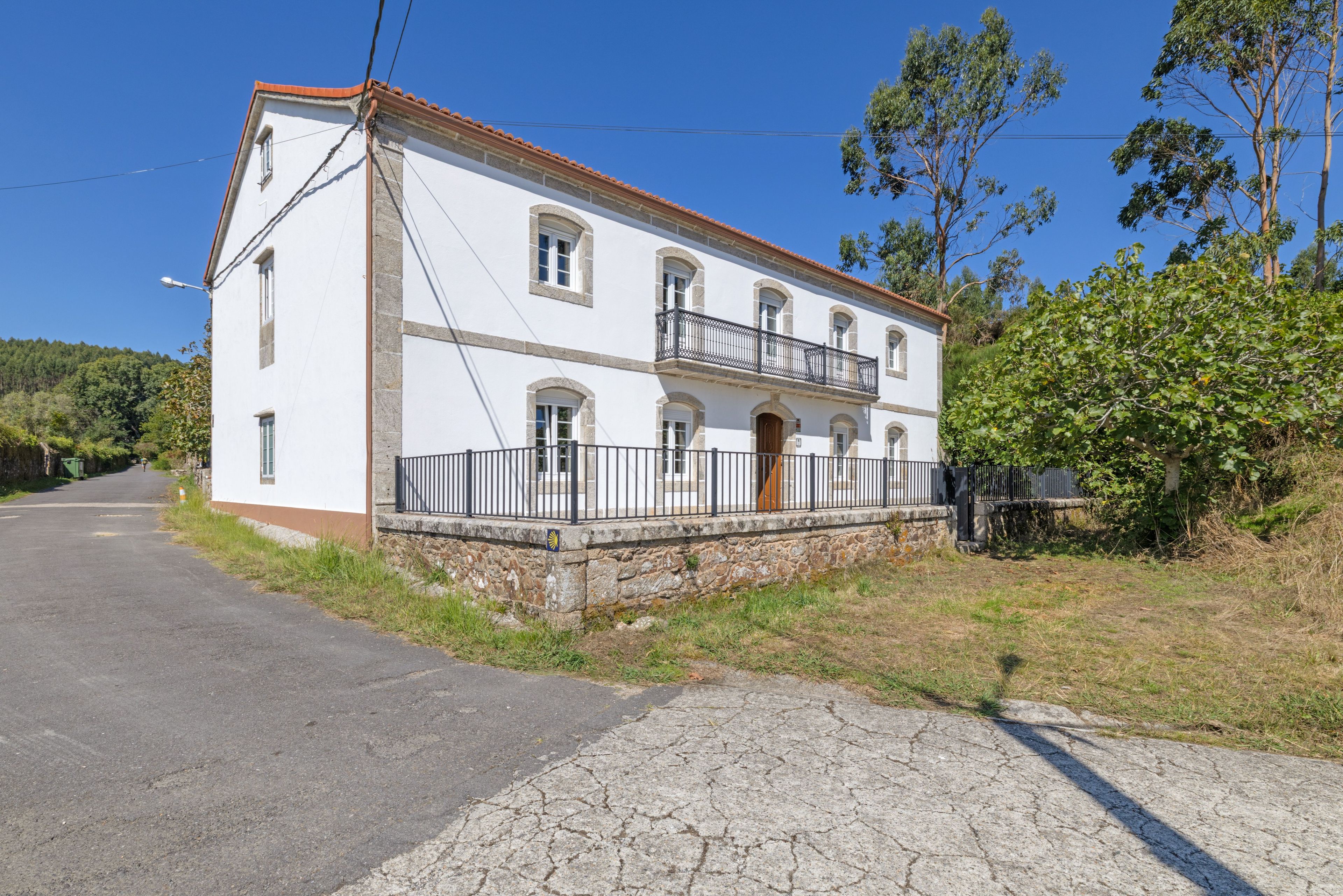A two-story building with a balcony, a stone foundation, and a clear sky.