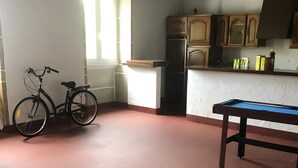 Een kamer met een pooltafel, een fiets en een koelkast.
