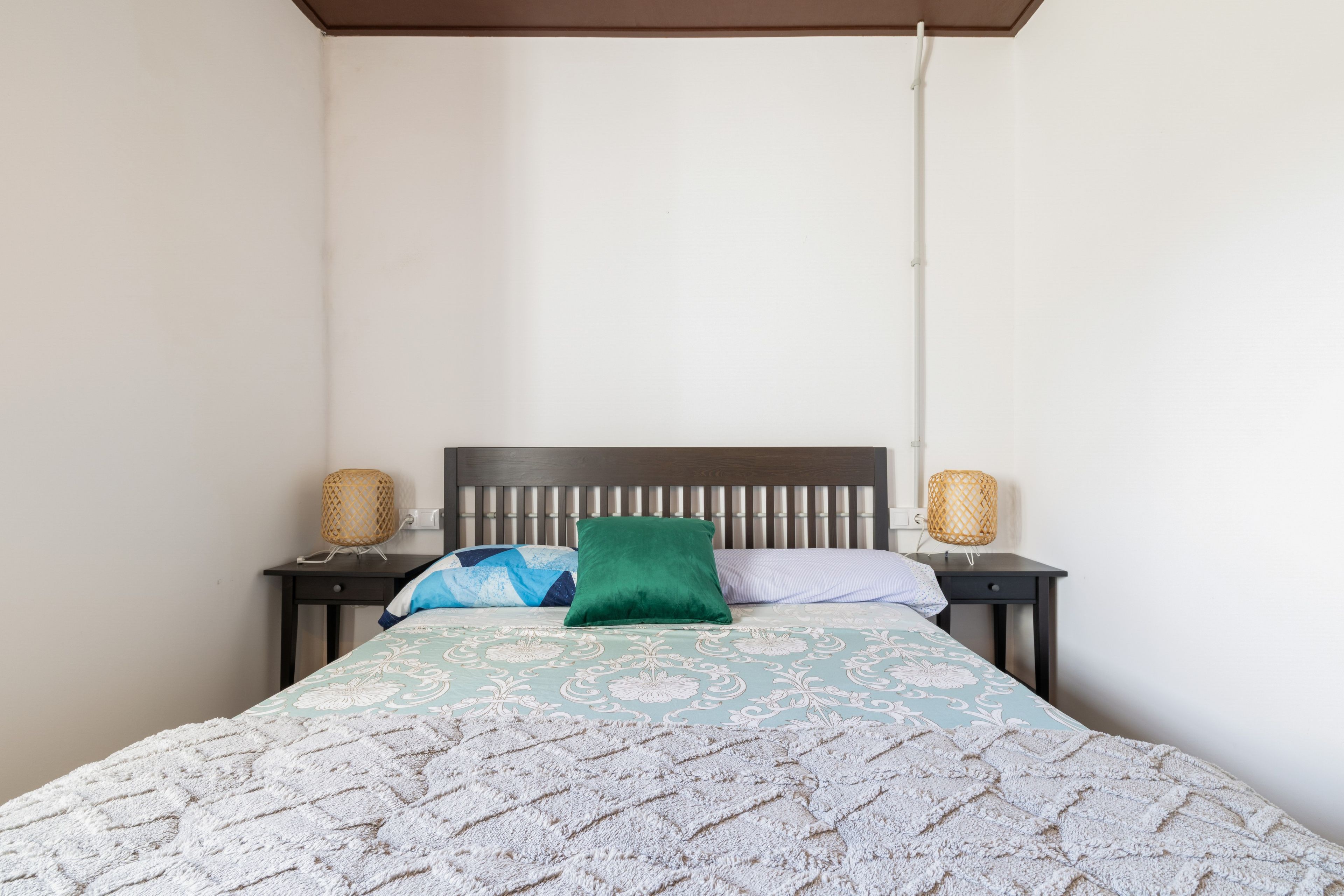 Una cama con un edredón estampado, dos lámparas de noche y un cabecero.