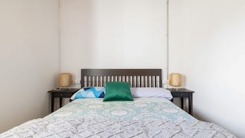 Una cama con un edredón estampado, dos lámparas de noche y un cabecero.