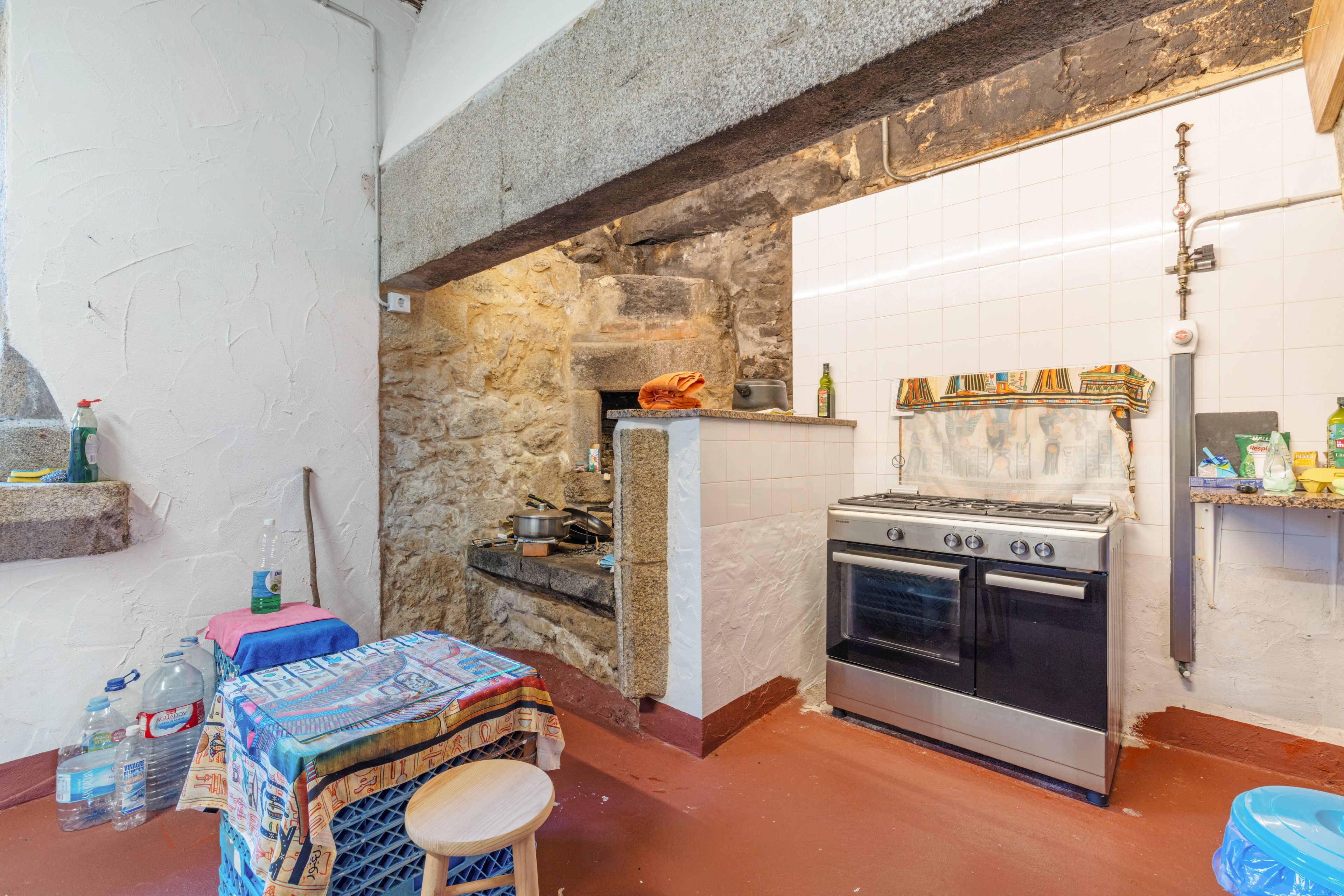 Una cocina con pared de piedra, salpicadero de azulejos y cocina a gas.
