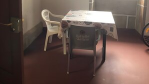 Een kamer met een tafel, twee stoelen, een raam met jaloezieën en een deur.