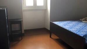 Een kamer met een bed, een klein tafeltje en een raam.