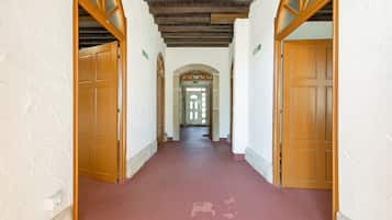 Un pasillo con puertas de madera y suelo rojo, que conduce a un acceso con panel de vidrio.