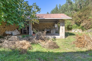 Una casa de piedra con tejado de baldosas, un porche cubierto y un muro de piedra.