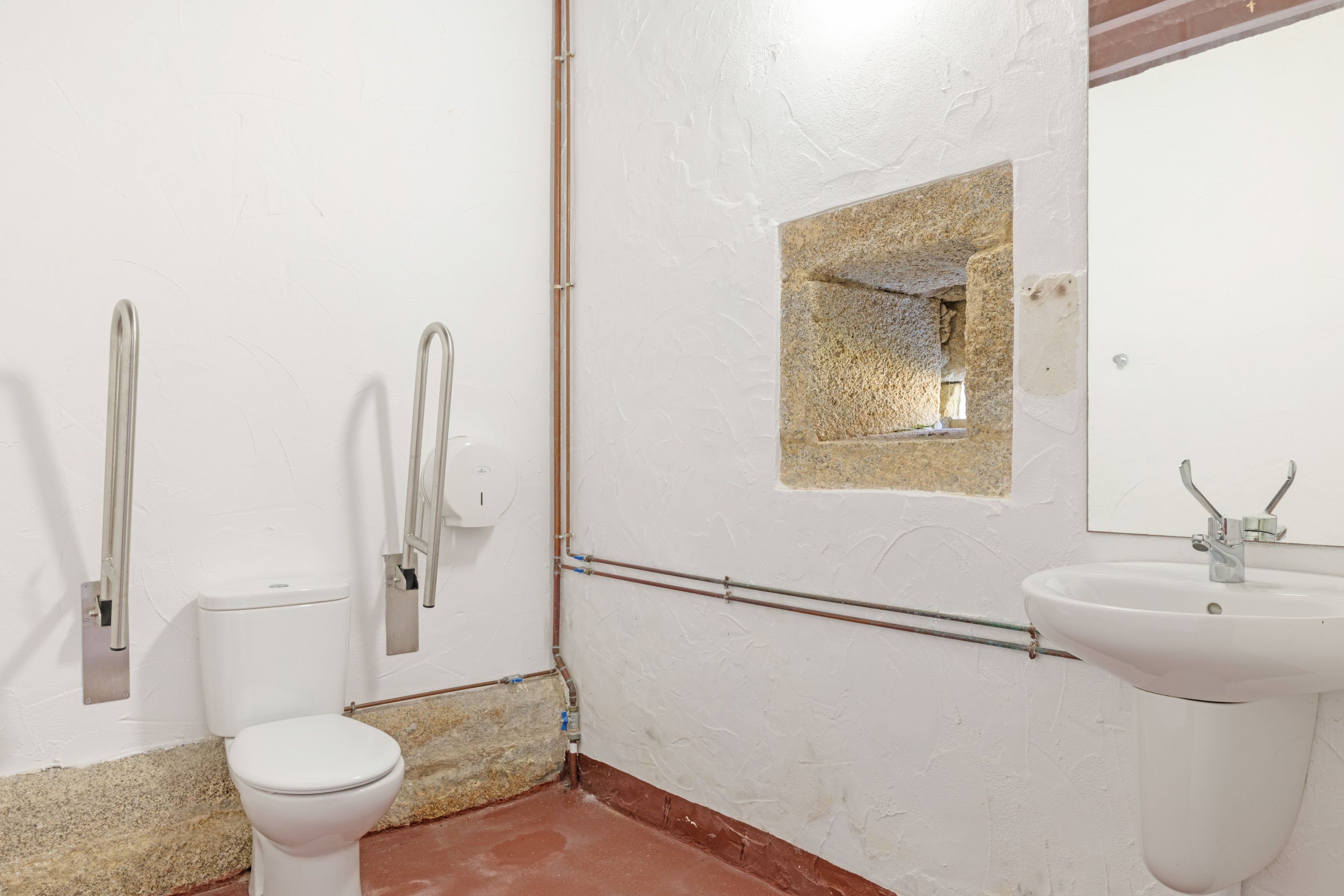 Un baño con inodoro, lavamanos y espejo.