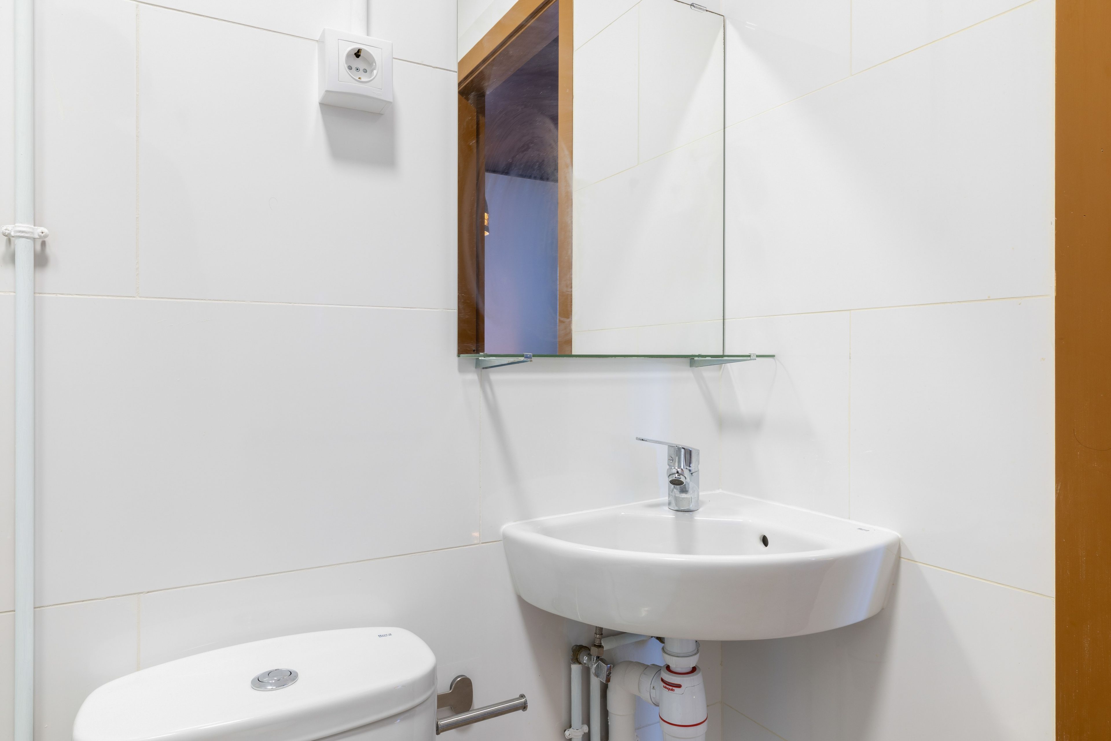 A bathroom with a white sink, a mirror, and a toilet.