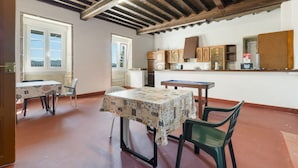 A dining area with a table and chairs, a kitchen with cabinets, and a view through a window.
