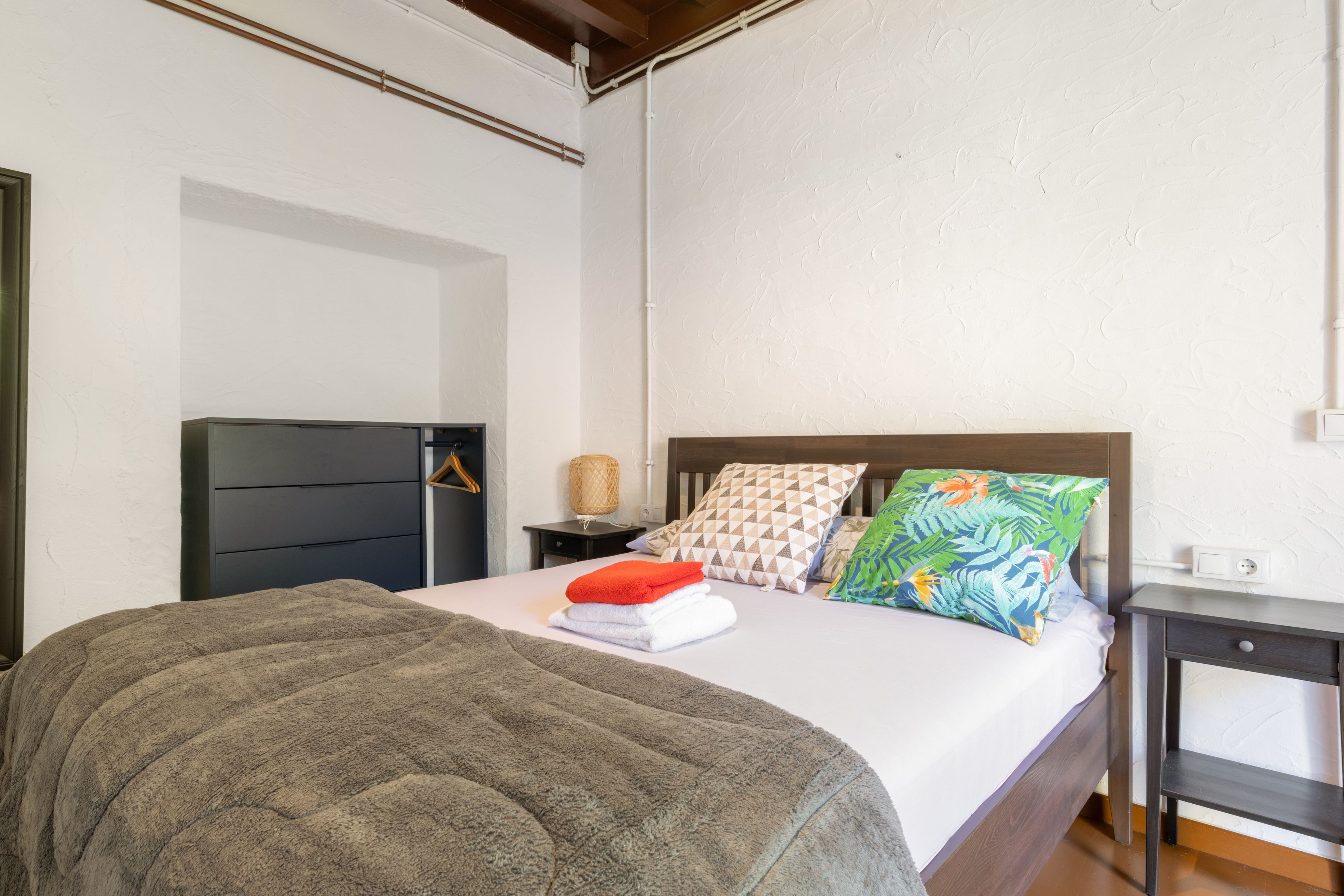 Un dormitorio con cama, mesita de noche, lámpara y armario.