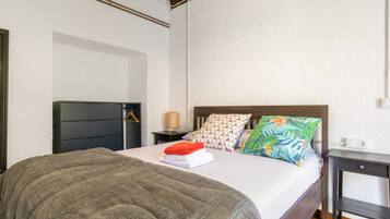 Un dormitorio con cama, mesita de noche, lámpara y armario.