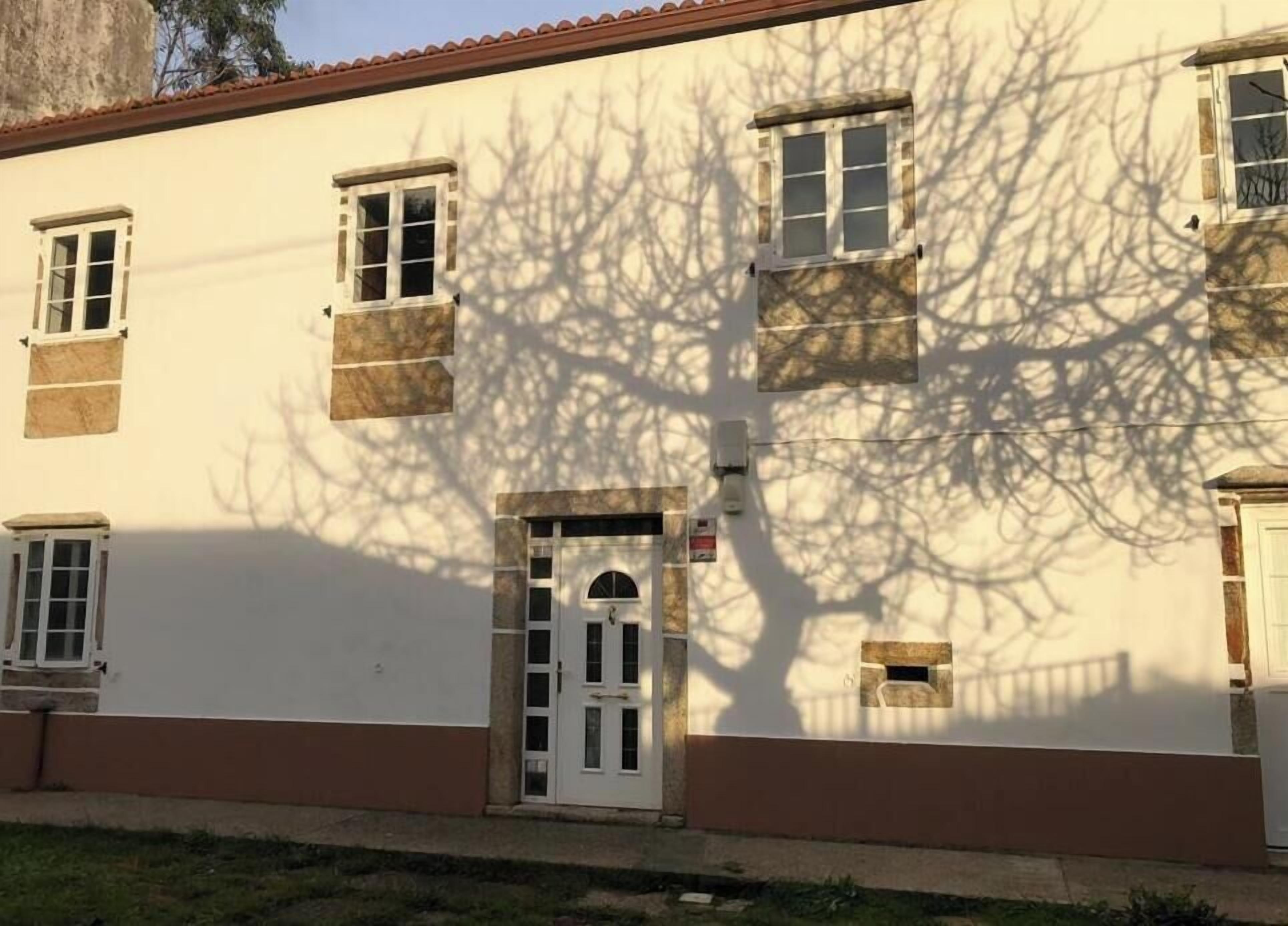 A building with a white facade, multiple windows, and a door with a small window above it.