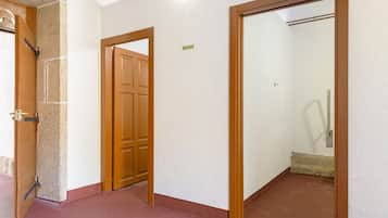Un pasillo con puerta de madera, pared blanca y suelo rojo.