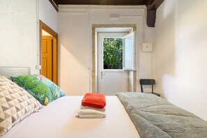 A room with a bed, a chair, and a window.