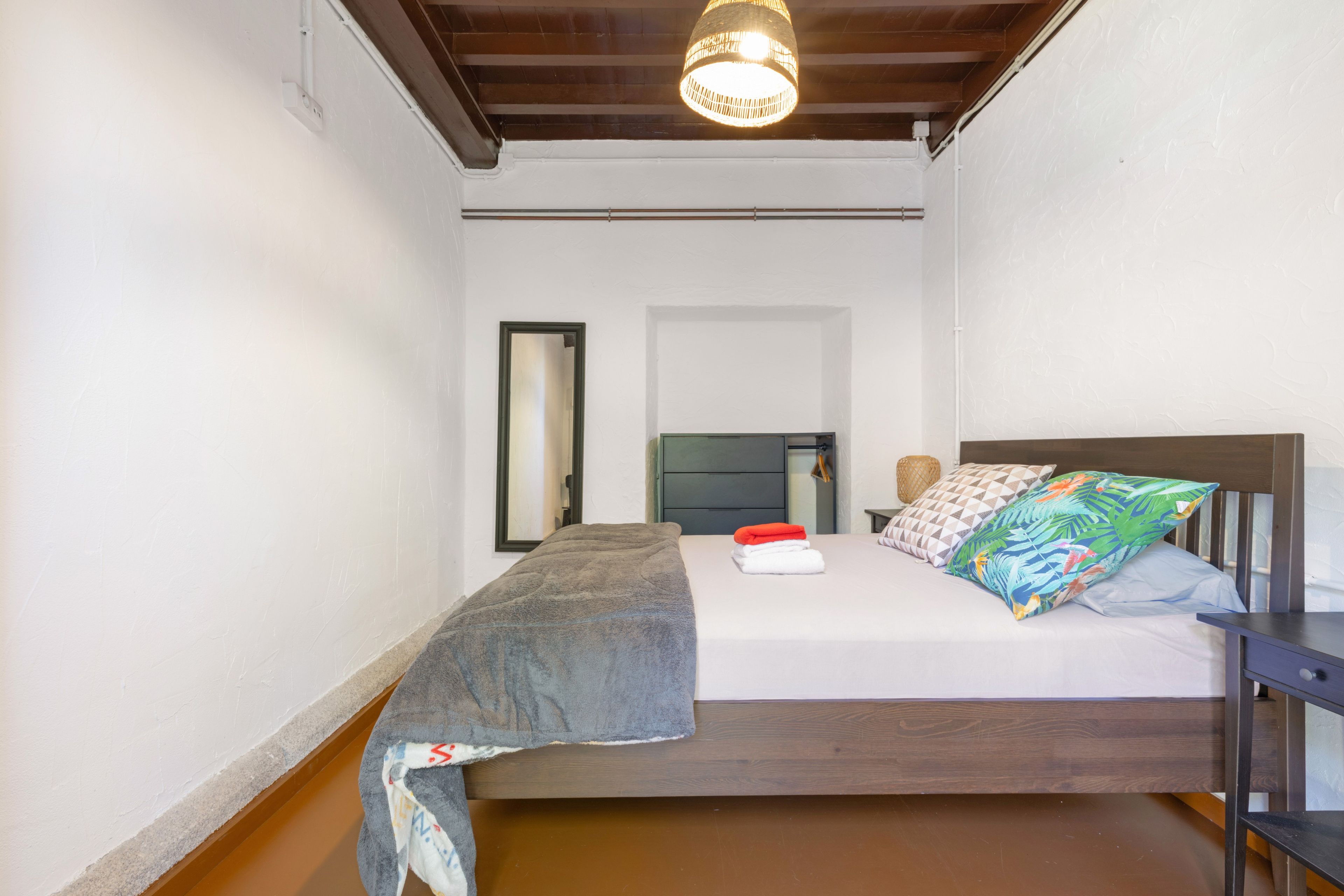 Un dormitorio con una cama, una mesita de noche, un espejo y una lámpara colgante.