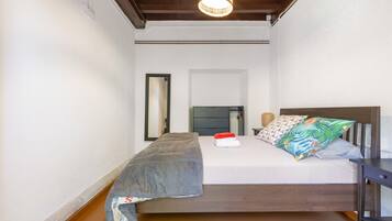 Un dormitorio con una cama, una mesita de noche, un espejo y una lámpara colgante.