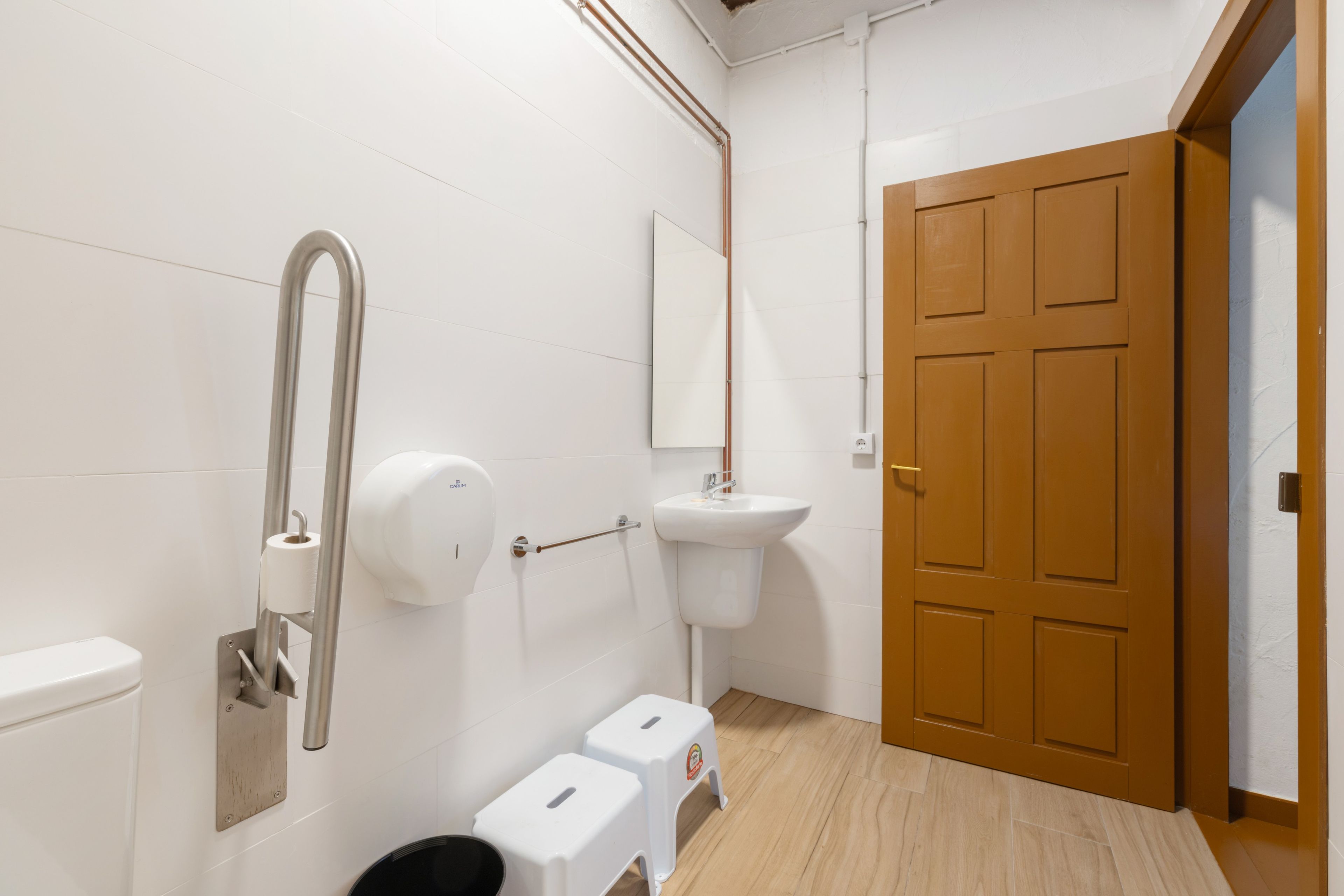 Een badkamer met een toilet, een handdroger, een wastafel en een houten deur.