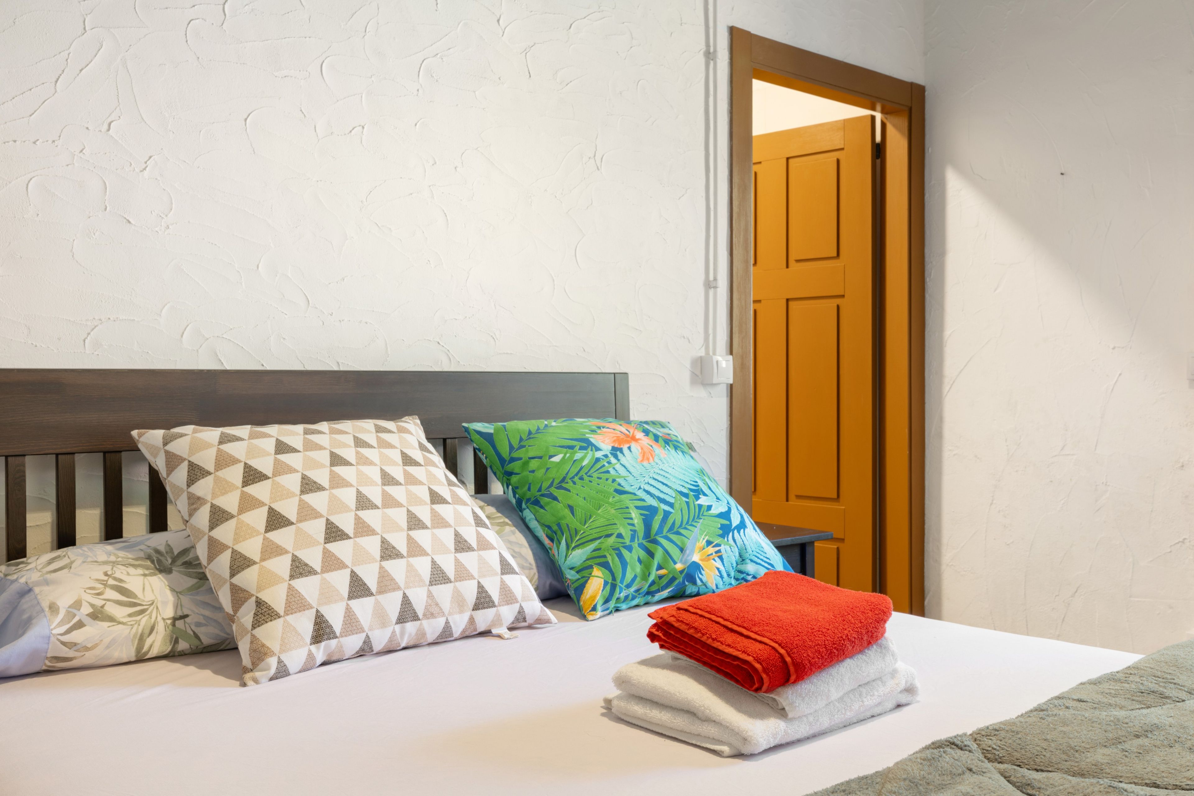 A bedroom with a bed, pillows, and a stack of towels.