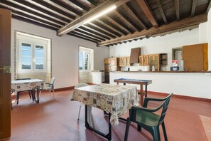 A dining area with a table and chairs, a kitchen with cabinets, and a view through a window.