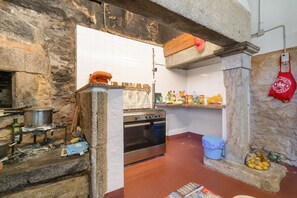A kitchen with stone walls, a stove, and various kitchen items.