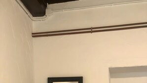 Una habitació amb un llit, una taula de nit, un mirall i una porta.