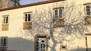 A building with a white facade, multiple windows, and a door with a small window above it. - Room 'Habitación Emma' with Mountain View, Shared Terrace and Wi-Fi (Moraime)