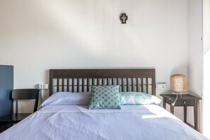 A bedroom with a bed, a chair, a bedside table, a lamp, and a wall-mounted light switch. - Room 'Habitación Emma' with Mountain View, Shared Terrace and Wi-Fi (Moraime)