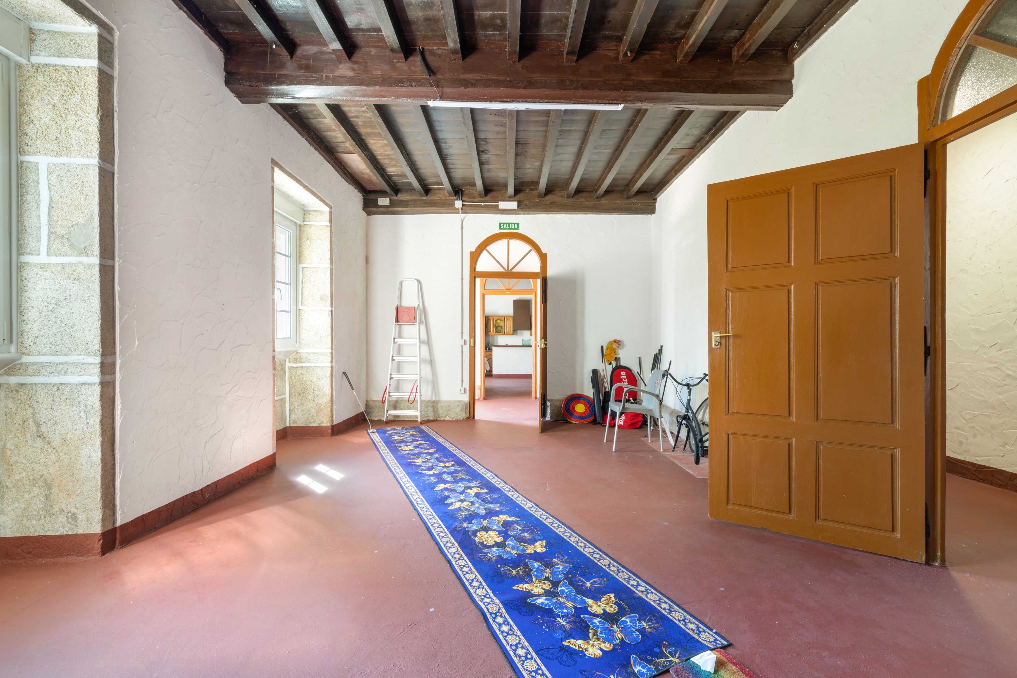 Un pasillo con alfombra azul, puertas de madera y una escalera.