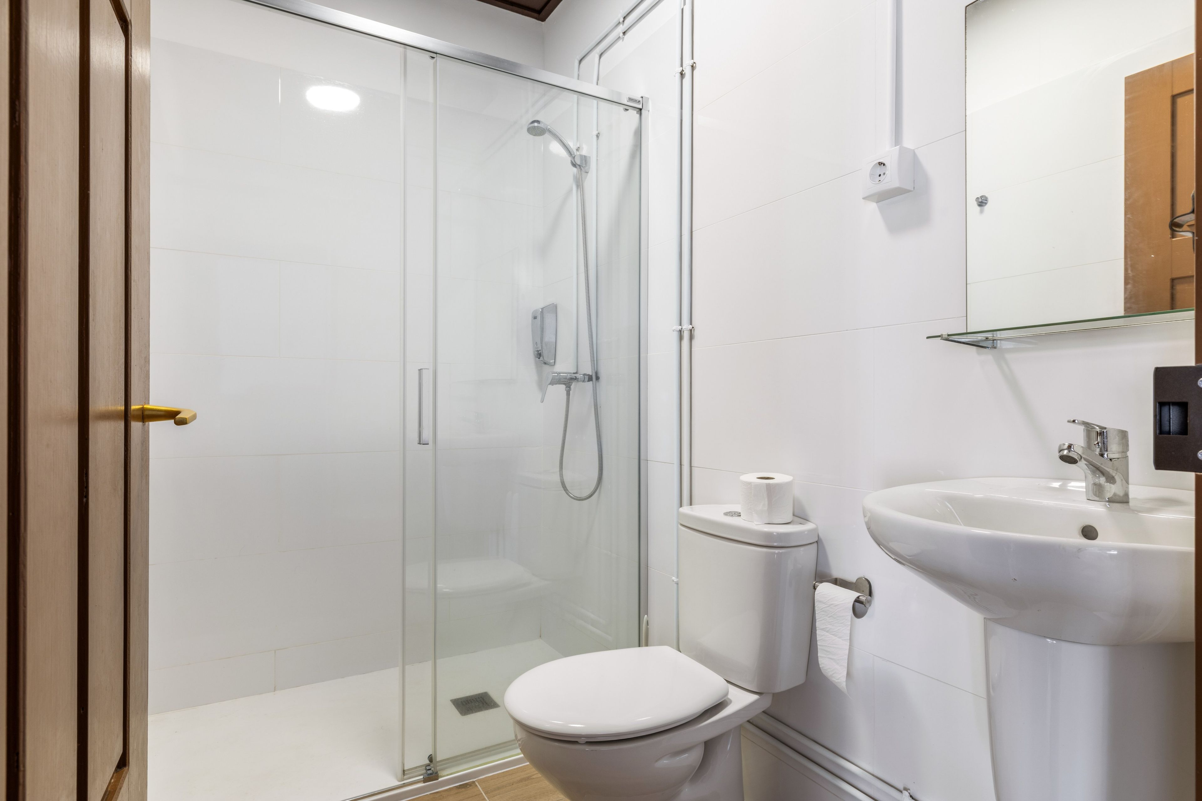 Ein modernes Badezimmer mit einer gläsernen Duschkabine, einer Toilette und einem Waschbecken mit Spiegel.