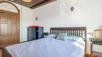 A bedroom with a bed, a wardrobe, a nightstand, and a wall-mounted lamp.