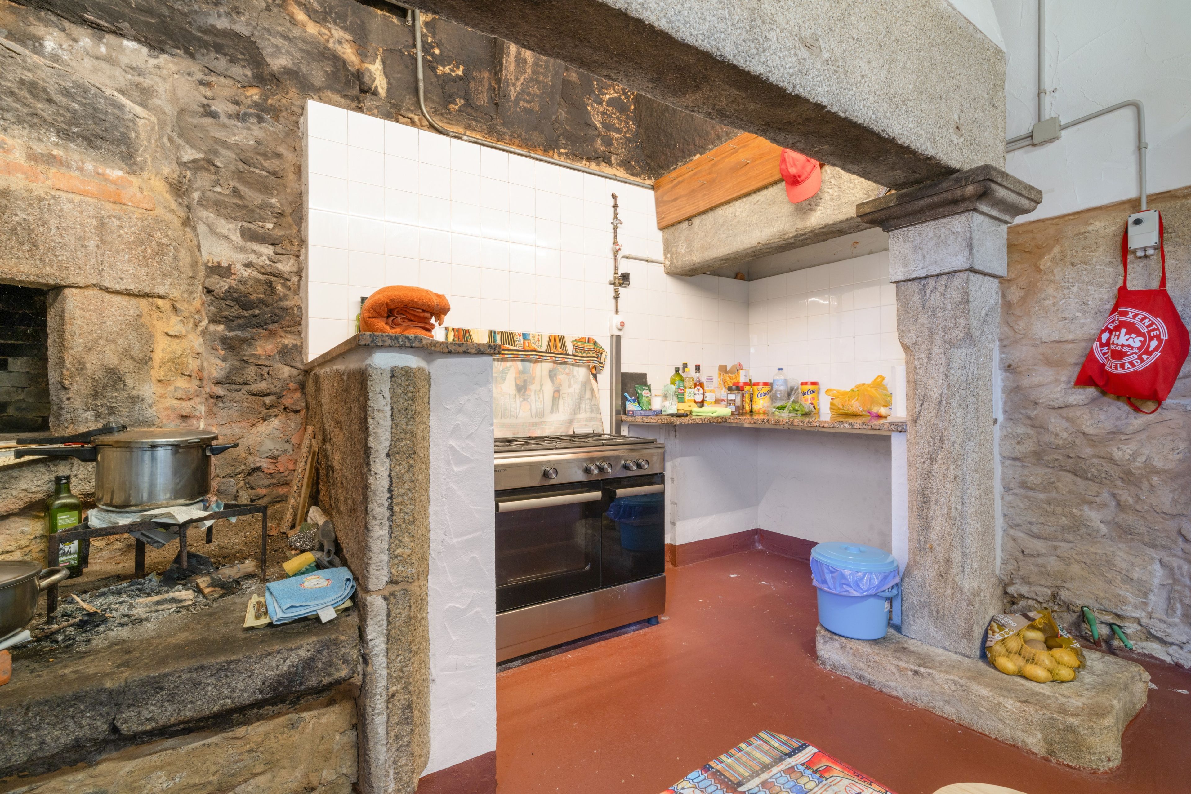 Una cocina con paredes de piedra, una estufa y diversos utensilios.