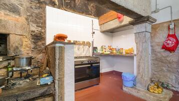 Una cocina con paredes de piedra, una estufa y diversos utensilios.