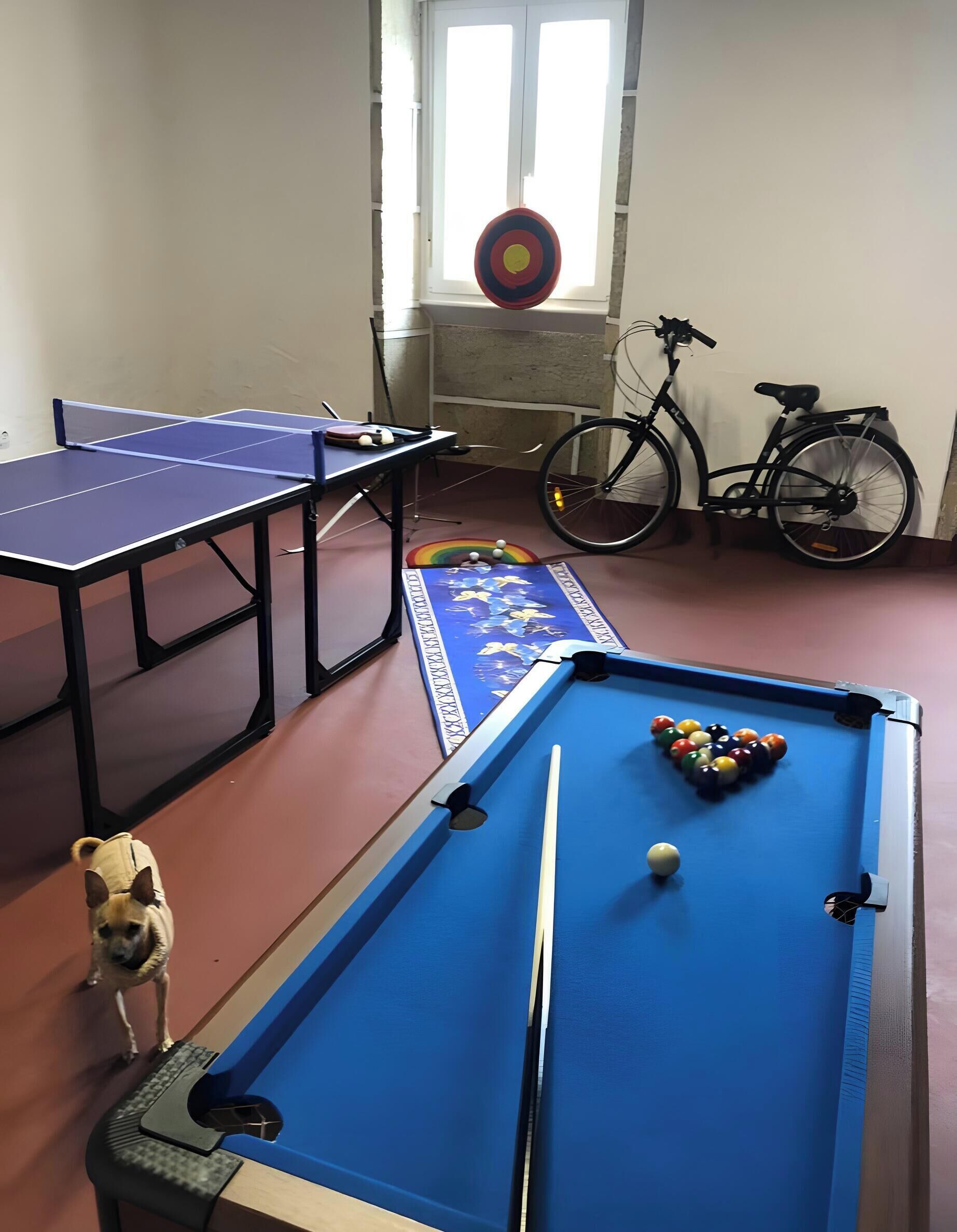 A room with a pool table, a ping pong table, and a bicycle.