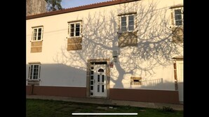 Ein Gebäude mit weißer Fassade, zahlreichen Fenstern und einer Tür mit kleinem Fenster darüber.