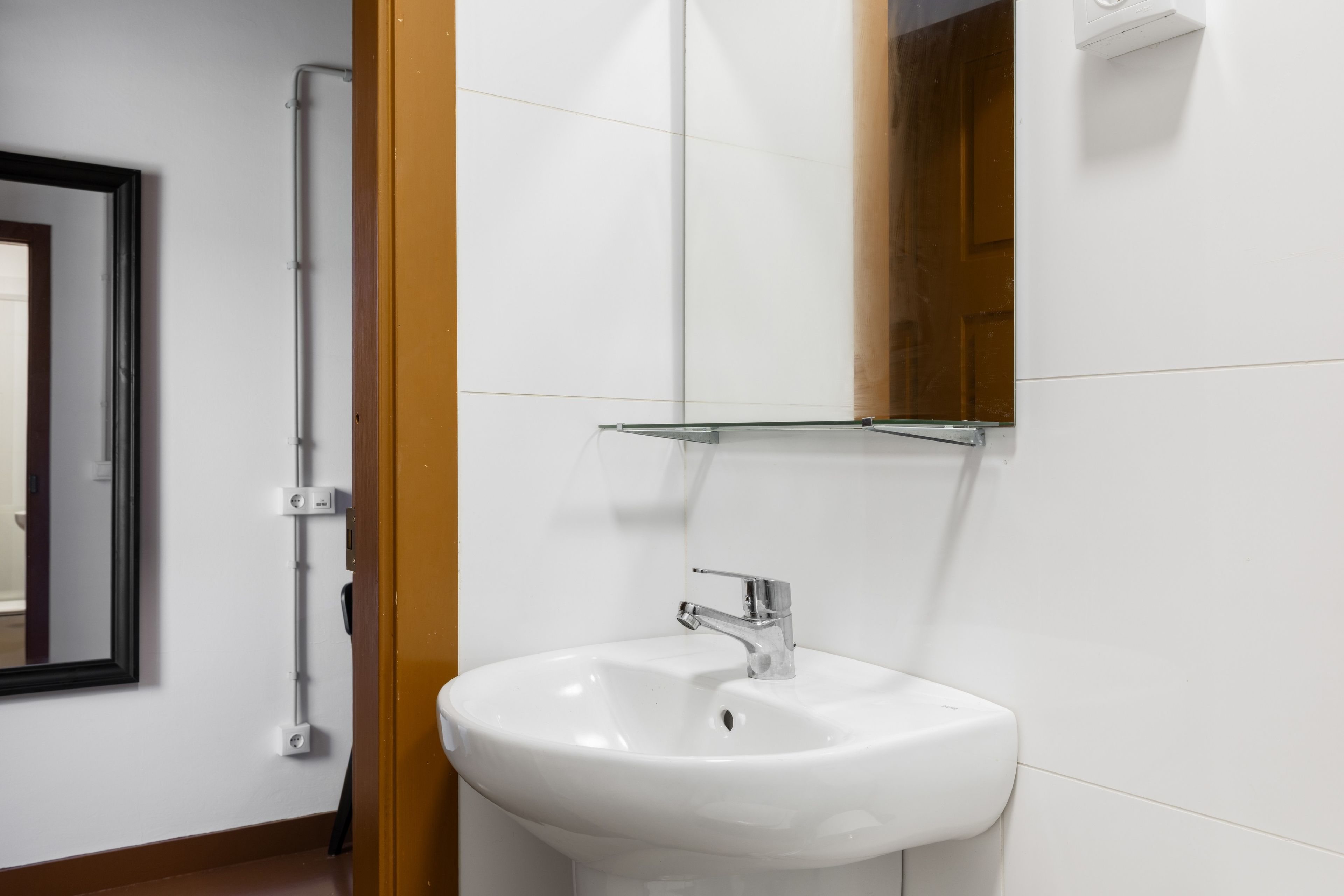 A bathroom with a white sink, a mirror, and a shower area.