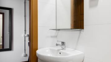 A bathroom with a white sink, a mirror, and a shower area.
