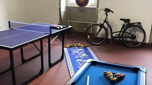 Ein Raum mit Billardtisch, Tischtennisplatte und einem Fahrrad.