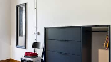A room with a chair, a large black wardrobe, and a framed picture on the wall.