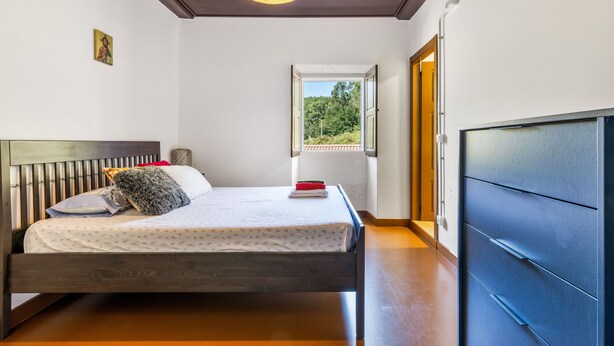 Un dormitorio con cama, ventana, puerta y lámpara en el techo.
