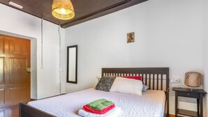 Un dormitorio con una cama de madera, una mesita de noche, una lámpara y una puerta.